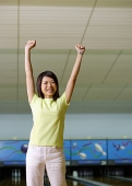 Woman standing at bowling alley, hands in the air - Asia Images Group