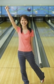 Woman standing at bowling alley, arm outstretched - Asia Images Group