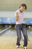 Woman at bowling alley, smiling, making a fist - Asia Images Group