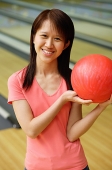 Woman at bowling alley with red bowling ball - Asia Images Group