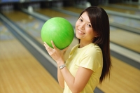 Woman at bowling alley holding green bowling ball - Asia Images Group