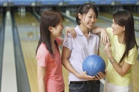 Three women at bowling alley, talking - Asia Images Group