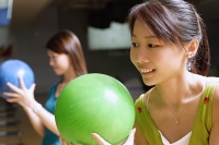 Two women holding bowling balls, preparing to bowl - Asia Images Group