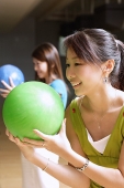 Two women with bowling balls, preparing to bowl - Asia Images Group