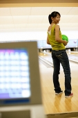Woman at a bowling alley, holding bowling ball - Asia Images Group