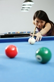 Woman holding pool cue, aiming at ball - Asia Images Group