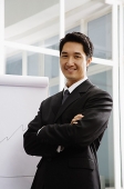 Businessman standing next to flipchart, smiling - Asia Images Group