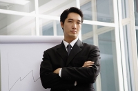 Businessman standing next to flipchart, looking at camera - Asia Images Group