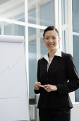 Businesswoman standing next to flipchart, smiling - Asia Images Group