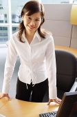 Businesswoman standing in cubicle, smiling at camera - Asia Images Group