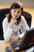 Businesswoman sitting in office cubicle, looking at camera - Asia Images Group