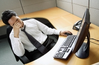 Businessman sitting at desk, hand covering face - Asia Images Group