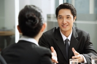 Businessman having discussion with businesswoman, over the shoulder view - Asia Images Group