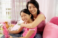 Mother embracing daughter, both looking at camera - Asia Images Group