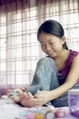 Girl in purple top sitting on bed, painting toenails - Asia Images Group