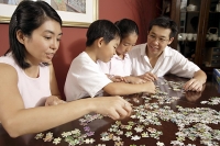 Family of four working on jigsaw puzzle - Asia Images Group