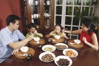 Family of four having dinner at home - Asia Images Group