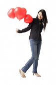 Woman holding red balloons, smiling - Asia Images Group