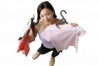 Woman holding up clothes, looking at camera - Asia Images Group