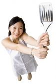 Woman holding up kitchen utensil - Asia Images Group
