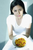 Young woman holding bowl of spices, looking at camera - Asia Images Group