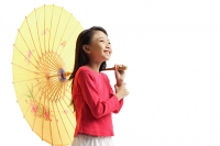 Girl holding yellow umbrella, standing against white background - Asia Images Group