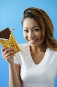 Woman holding a bar of chocolate, smiling - Asia Images Group