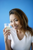 Woman holding a glass of milk, smiling at camera - Asia Images Group