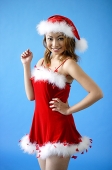 Woman wearing Santa hat and red dress, smiling at camera - Asia Images Group