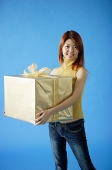 Woman carrying big gift box, smiling - Asia Images Group