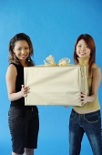Two woman carrying big gift box, smiling - Asia Images Group