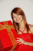 Woman holding red gift box, smiling - Asia Images Group
