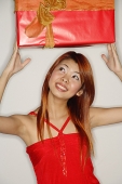 Woman holding red gift box over her head - Asia Images Group