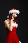 Woman wearing Santa hat and red dress, shouting - Asia Images Group