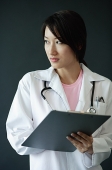 Female doctor, holding clipboard, looking away - Asia Images Group