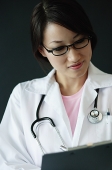 Female doctor looking at clipboard - Asia Images Group