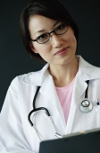 Female doctor holding clipboard, looking at camera - Asia Images Group
