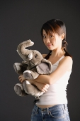 Young woman with braids hugging stuffed toy elephant - Asia Images Group