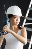 Young woman in hard hat, holding drill - Asia Images Group