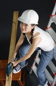 Young woman in hard hat, sitting on ladder - Asia Images Group