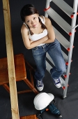 Young woman sitting on ladder, arms crossed, looking at camera - Asia Images Group