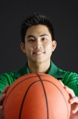 Young man holding basketball, looking at camera - Asia Images Group
