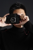 Young man dressed in black looking through camera - Asia Images Group