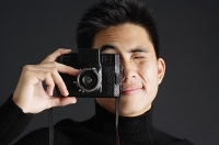 Young man looking through camera - Asia Images Group