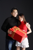 Couple standing side by side, holding gift - Asia Images Group