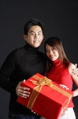Couple holding gift, looking at camera - Asia Images Group