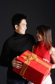 Couple holding gift, looking at each other - Asia Images Group