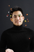 Young man dressed in black throwing multi coloured candy in the air - Asia Images Group