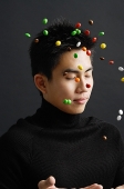 Young man dressed in black, throwing multi coloured candy in the air - Asia Images Group