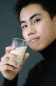 Young man holding glass of milk, looking at camera - Asia Images Group